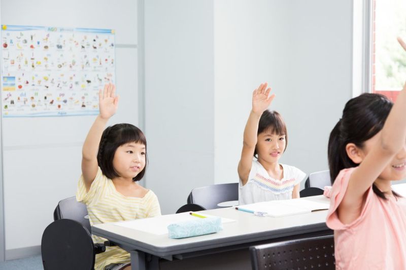 教室で手を挙げる小学生